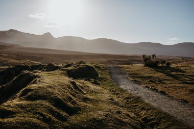 Manzaralı bir yolun Isle of Skye, İskoçya ile gün batımında, dağlar içinde belgili tanımlık geçmiş olacak..