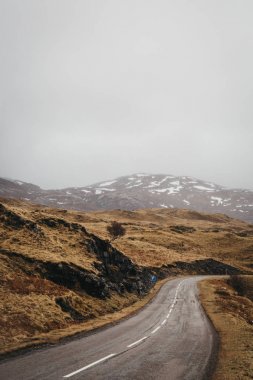 Yol geçmekte İskoçya Highlands Lochinver yakınındaki bir sisli bahar gününde.