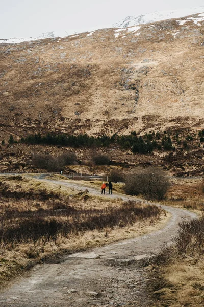 苏格兰高地白雪皑皑山和湖边漫步的不明身份的人的剪影 — 图库照片