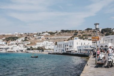 Güneşli bir günde Hora 'da insanlar suyun kenarında yürüyor. (Mykonos Kasabası