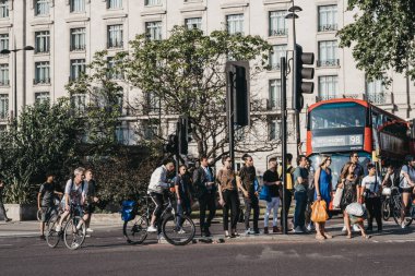 Yayalar ve bisikletçiler Marbl 'ın yanındaki yolu geçmek için bekliyorlar.