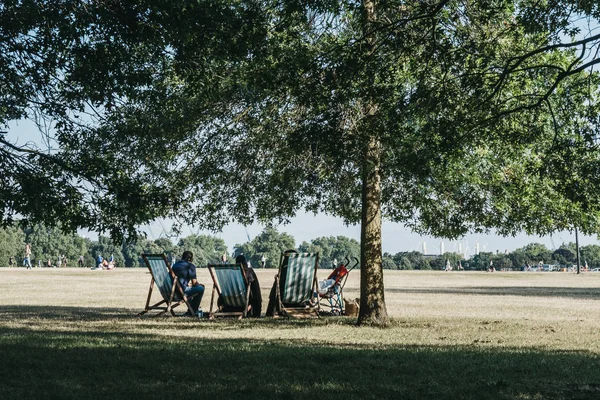 Mensen ontspannen op ligstoelen in een park op een warme zomerdag in — Stockfoto