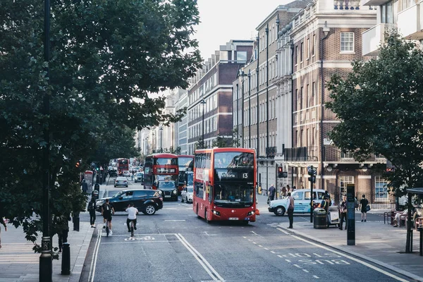 Cyclists, red double decker buses and taxis on a street in Londo — Stock Photo, Image