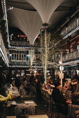 People sitting at the tables inside Kingly Court decorated with  clipart