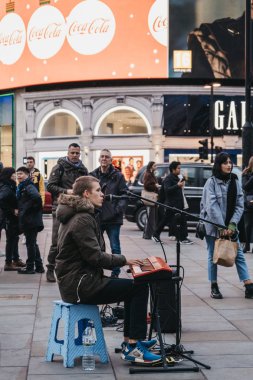 Londra Piccadilly Sirki 'nde klavye çalıp şarkı söyleyen bir sokak müzisyeni.