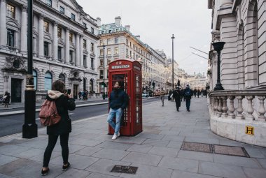 Turistler Regent Caddesi 'ndeki kırmızı telefon kulübesinde fotoğraf çekiyor.