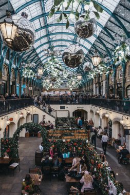İnsanlar Covent Garden 'daki bir kafenin açık masalarında oturuyorlar.