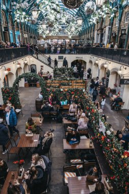 İnsanlar Covent Garden 'daki bir kafenin açık masalarında oturuyorlar.