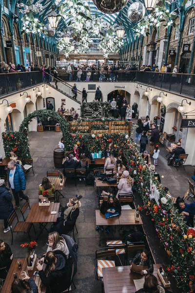 İnsanlar Covent Garden 'daki bir kafenin açık masalarında oturuyorlar.