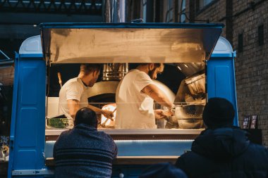 İnsanlar Spitalfi içinde bir Sud Italia pizza tezgahından yiyecek satın alma