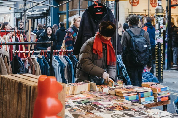Frau blättert in Büchern an einem Marktstand in der Backsteingasse, London, Großbritannien — Stockfoto