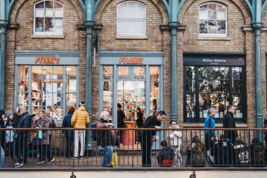 İnsanlar Covent 'teki dükkanların önünde ayakta ve yürüyorlar. 