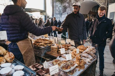 Londra, Uk - 29 Kasım 2019: Londra 'nın en büyük ve en eski gıda pazarlarından biri olan Borough Market' teki bir ekmek tezgahında cep telefonuyla ödeme yapan adam.