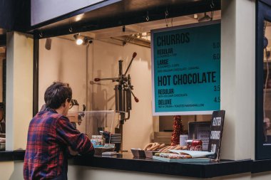 Londra, Uk - 26 Kasım 2019: Adam Camden Market, Londra 'daki churros standından yemek sipariş ediyor. 1974 'te 16 tezgahla başlayan Camden Market, Londra' nın en işlek perakende satış merkezlerinden biri..
