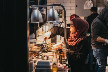 Londra, Uk - 26 Kasım 2019: Londra 'daki Camden Market' te tesettürlü Müslüman bir kadın yemek pişiriyor. 1974 'te 16 tezgahla başlayan Camden Market, Londra' nın en işlek perakende satış merkezlerinden biri.