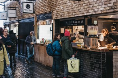 Londra, Uk - 26 Kasım 2019: Londra 'nın en işlek perakende satış merkezlerinden biri olan Londra' nın Camden Market kentindeki Magic Falafel 'den vegan gıda sipariş eden kadınlar.