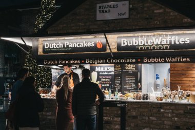 Londra, Uk - 26 Kasım 2019: İnsanlar akşamları Camden Market, Londra 'da bir tezgahta Hollanda gözlemesi sipariş ediyorlar. 1974 'te 16 tezgahla başlayan Camden Market, Londra' nın en işlek perakende satış yerlerinden biri..