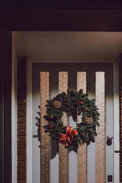Beyaz Kapısında Kırmızı Bir Fiyonk Olan Noel Çelengi Akşam Seçici — Stok fotoğraf