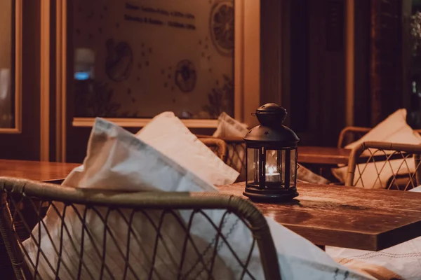 Close up of a candle lamp on an outdoor table at night, cosy atmosphere, selective focus.