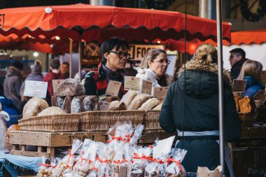 Londra, Uk - 29 Kasım 2019: Londra 'nın en büyük ve en eski gıda pazarlarından biri olan Borough Market' teki ekmek ve pastanede satıcı, müşterilerle etkileşimde, seçici odaklı.