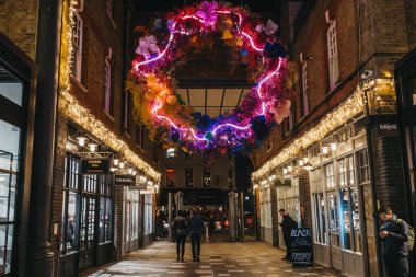 London, UK - November 29, 2019: People walk under Christmas in Spitalfields Market, one of the finest Victorian Market Halls in London with stalls offering fashion, antiques and food. Selective focus.