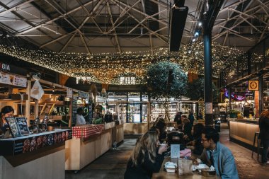 London, UK - November 29, 2019: People and stalls inside Spitalfields Market, one of the finest Victorian Market Halls in London with stalls offering fashion, antiques and food. Selective focus.