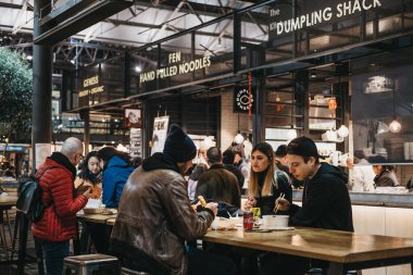 Londra, Uk - 14 Aralık 2019: Londra 'nın en iyi Viktorya Marketlerinden biri olan Spitalfields Market' teki masalardaki insanlar moda, antika ve yiyecek sunuyorlar. Seçici odak.