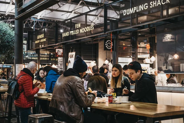 ロンドン 12月14 2019 人々は ファッション アンティーク 食べ物を提供する屋台でロンドンで最高のビクトリア朝市場ホールの1つであるSpitalfield Market内のテーブルにいます 選択的焦点 — ストック写真