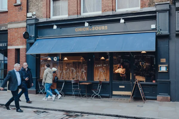Londra, İngiltere - Mart 06, 2020: Covent Garden 'daki Piliçler ve Sours Restoranı Cephesi, Londra' da bir sürü dükkan ve restoranı olan ünlü bir turistik bölge, insanlar geçip gidiyor, hareket bulanıklığı.