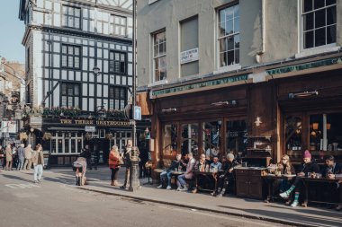 Londra, İngiltere - Mart 06, 2020: Güneşli bir bahar gününde, Londra 'nın LGBTQ + barlarıyla ünlü bir bölgesi olan Soho' daki Cafe Boheme 'nin açık masalarında oturan insanlar.