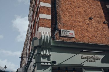 Londra, İngiltere - 6 Mart 2020: Covent Garden 'daki Langley Court' ta güneşli bir bahar gününde Londra 'nın barları, restoranları ve kafeleri ile ünlü bir binadaki sokak adı tabelası.