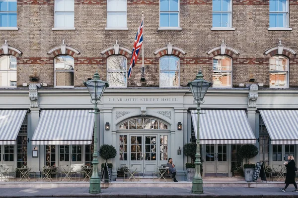 Londra, İngiltere - 6 Mart 2020: Soho 'daki Charlotte Street Hotel' in önünde sigara içen kadın, güneşli bir bahar gününde Londra 'nın barları, restoranları ve kafeleri ile ünlüdür..