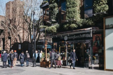 Londra, İngiltere - Mart 06, 2020: Covent Garden 'da güneş gözlüğü dükkânı, Londra' da bir sürü dükkânı ve restoranı olan ünlü bir turizm bölgesi, insanlar yanından geçiyor, hareket bulanıklığı.
