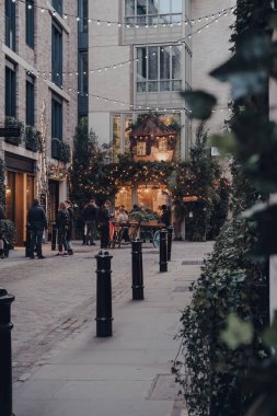 Londra, İngiltere - Mart 06, 2020: Covent Garden 'daki bir barın dışındaki insanların uzak görüşü, Londra' da bir sürü dükkan ve restoranı olan ünlü bir turizm alanı, seçici odaklı.