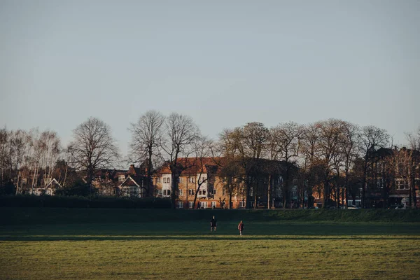 ロンドン 2020年3月22日ロンドン エンフィールドのパーマーズ グリーンの公共公園ブルームフィールド パークでボールをプレーする2人の遠望黄金の時間の間に — ストック写真