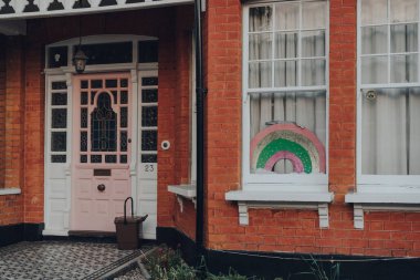 Londra, İngiltere - 12 Nisan 2020: Coronavirus yüzünden insanlar birbirlerini desteklerken Londra 'da bir evin penceresinde el yapımı gökkuşağı tabelası sergilendi. Seçici odak.