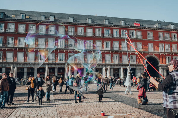 Madrid, Spain - January 26, 2020: Man making soap bubbles in Plaza Mayor, a major public space in the heart of Madrid, the capital of Spain renowned for its rich repositories of European art.