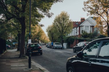 Londra, İngiltere - 22 Nisan 2020: Adam İngiltere 'nin Kuzey Londra' daki Londra Enfield İlçesi 'nde bir banliyö bölgesi olan Palmers Green' de park etmiş bir caddede arabaların yanından geçiyor. Seçici odak.