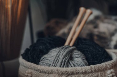 Bir sepetin içindeki yumak yumağı, büyük ahşap örgü iğneleri, sığ odak.