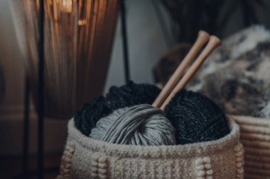 Bir sepetin içindeki yumak yumağı, büyük ahşap örgü iğneleri, sığ odak.