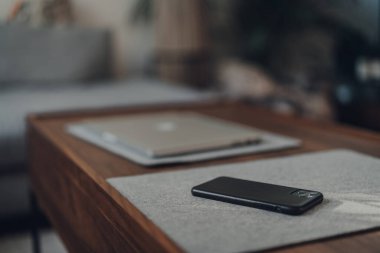 Londra, İngiltere - 5 Mayıs 2020: iPhone 11 Pro Max Apple 'ın evdeki bir masada, dizüstü bilgisayar arka planda, seçici odaklanma. Dünyanın dört bir yanındaki insanlar Coronavirüs yüzünden evden çalışıyor.