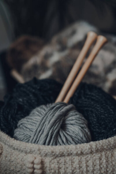 Крупный план шаров пряжи внутри корзины, с большими деревянными вязальными иглами, мелким фокусом
.