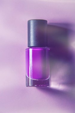 Lila, mor vernik bir şişe siyah kapaklı bir mor üzerinde parlak ışık pembe arka plan.