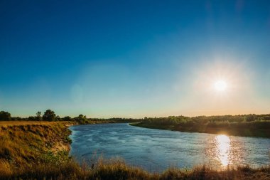 Günbatımı üzerinde nehir ve küçük bir orman