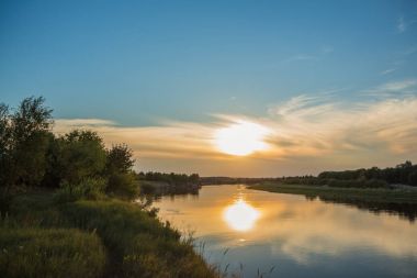 Sarı güneşin ve bulutların birlikte günbatımı zamanı nehirde