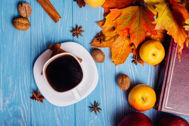 Üzerinde mavi bir woo bir kitap ve bir fincan sade kahve ile akçaağaç yaprakları