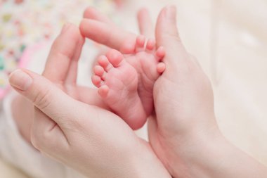 Anne küçük bebek bacakları elinde tutar.