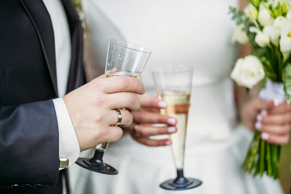 O noivo segura uma taça de champanhe ao lado da noiva — Fotografia de Stock