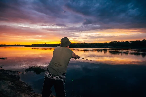 Fiskare vid floden på en solnedgång bakgrund — Stockfoto