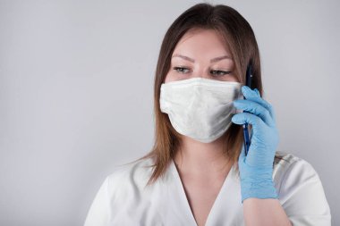 Doktor, hemşire telefonda konuşuyor. Genç doktor, sağlık görevlisi çağrıyı kabul ediyor. Özel korumalı eldivenli genç bayan..
